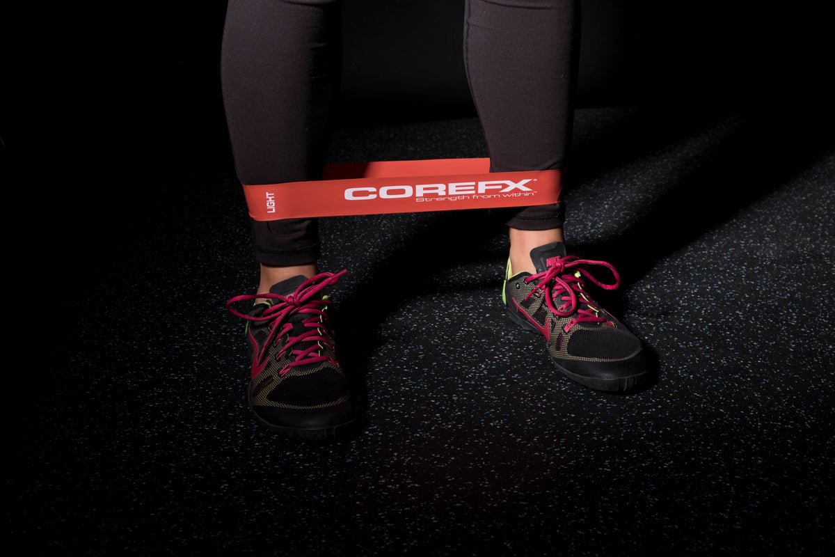 Person using a COREFX resistance band on a dark floor COREFX Pro Loop Resistance Band Set 4-Pack